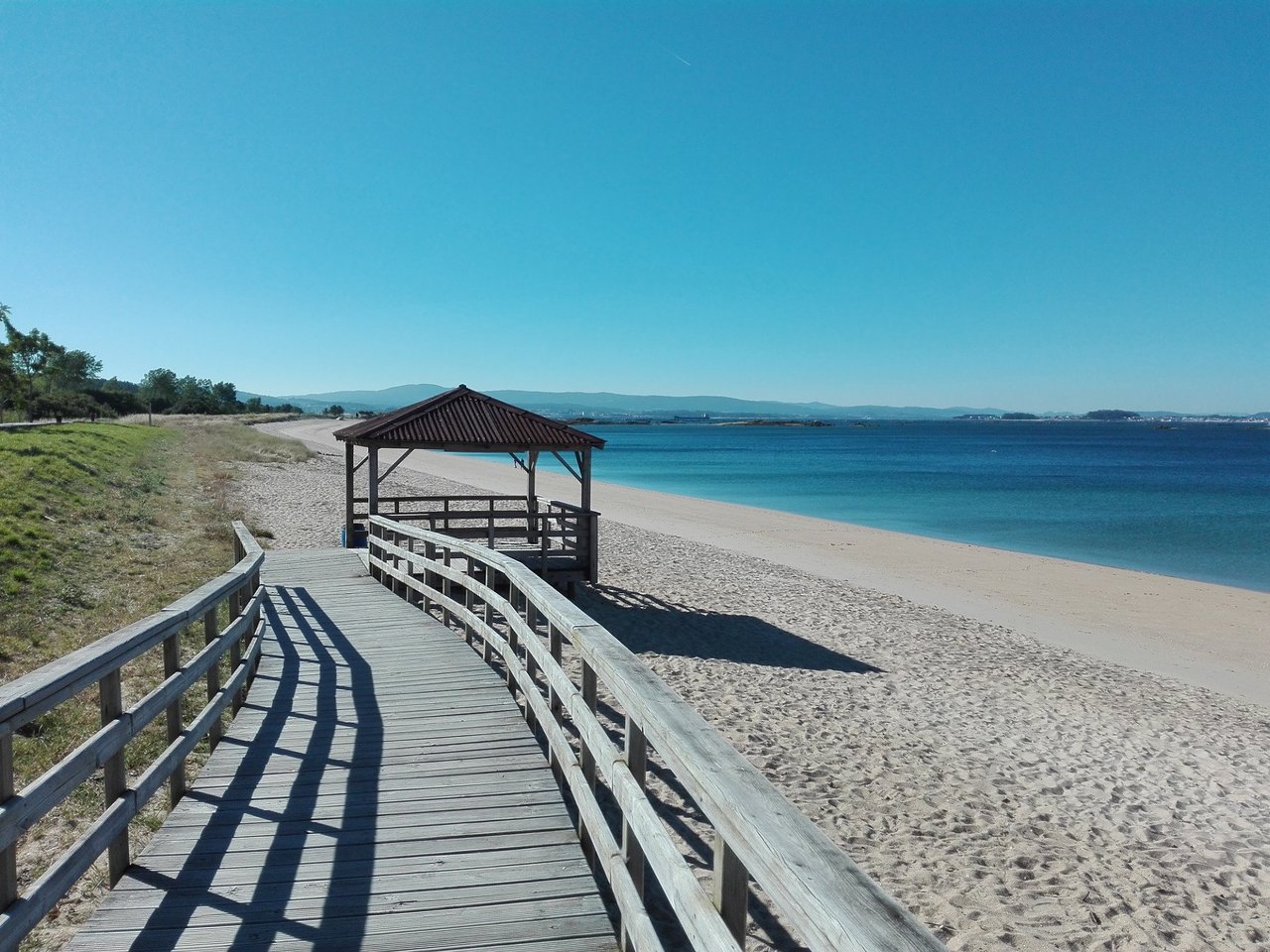 Pasarela de madera sobre la arena de la playa en Boiro